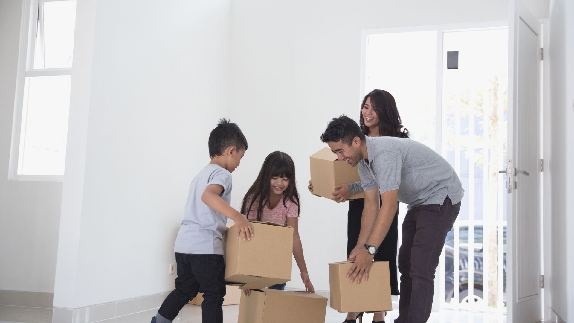 Inclusion equality asian family moving in packages boxes white room patio door