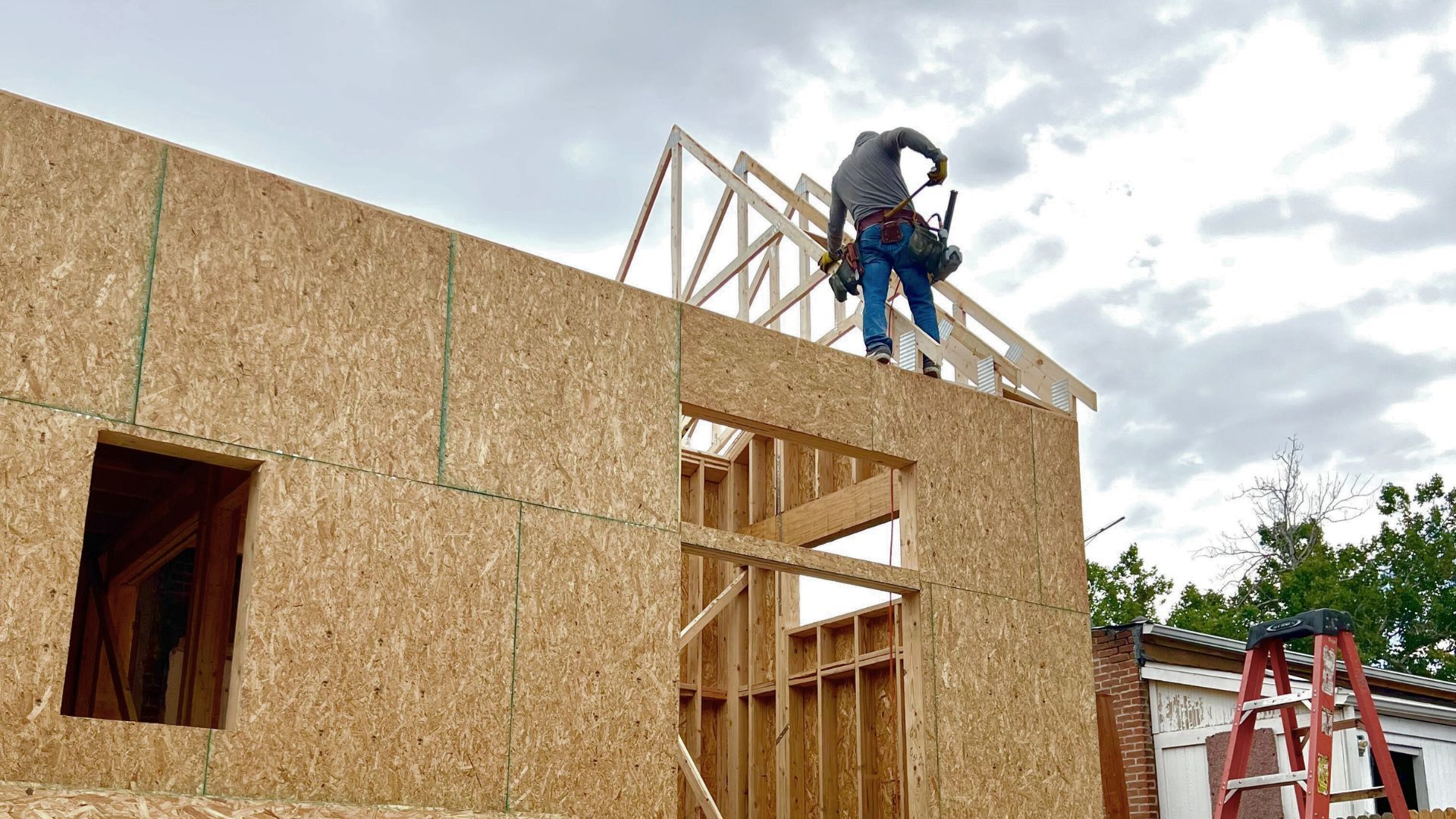 Colorado 2026 Building Code for Denver Custom Homes and ADUs Sustainable Design Build subcontractor taking measurements of roof trusses while framing a Denver Home Addition Project