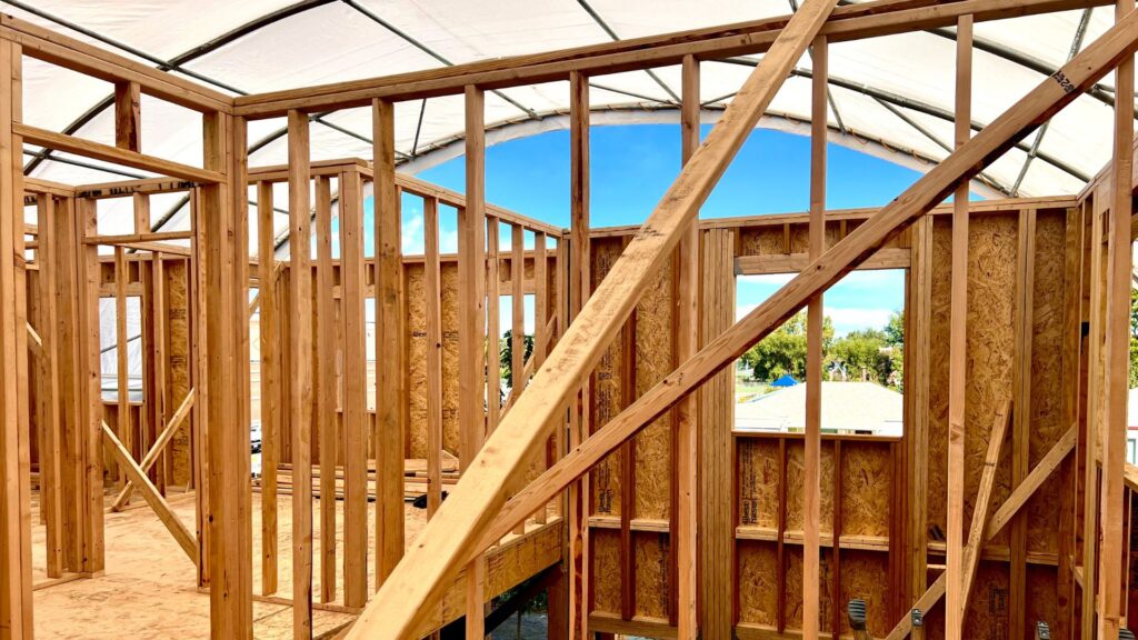 Construction and wood framing of a second story home with weather proofing solutions erected overhead in Denver.
