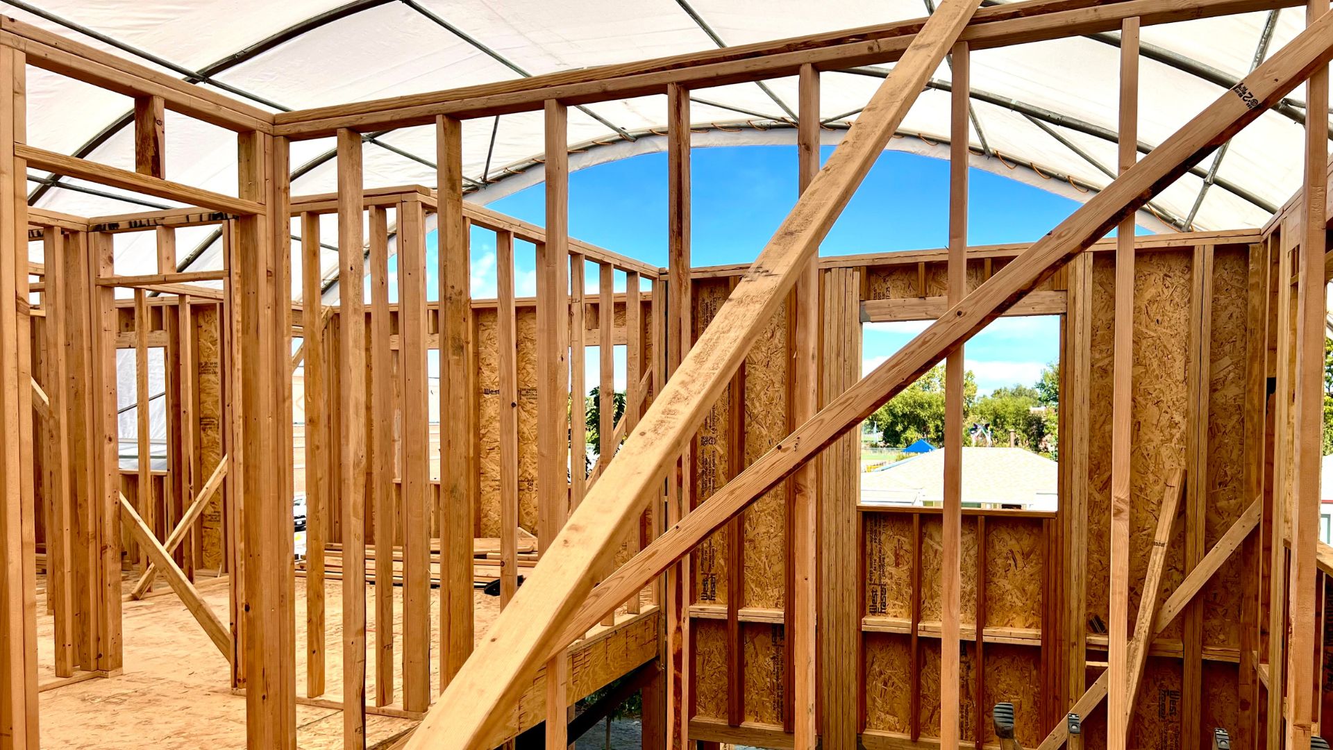 Construction and wood framing of a second story home with weather proofing solutions erected overhead in Denver.