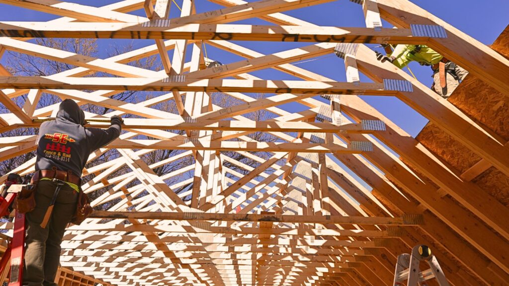 Overhead framing with two workers with Sustainable Design Build erecting roof trusses in a Denver Bungalow Home in October