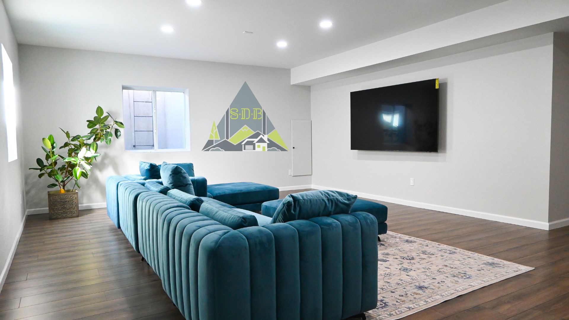 Finished basement in wheat ridge showing teal couch hardwood floors big open floor layout and bright windows