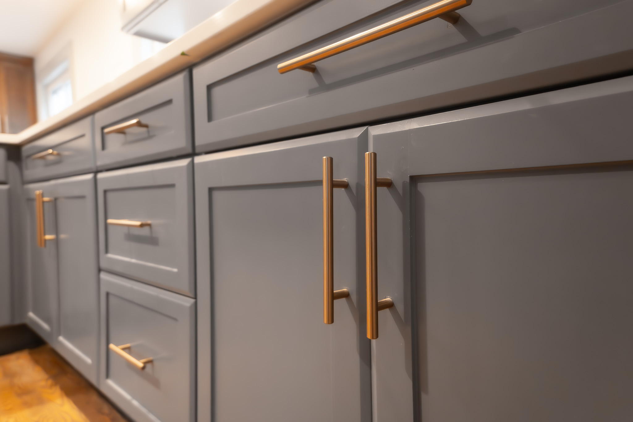 littleton home remodels custom cabinet blue grey lowers with brass and gold hardware supporting white quartz like countertop in newly remodeled kitchen