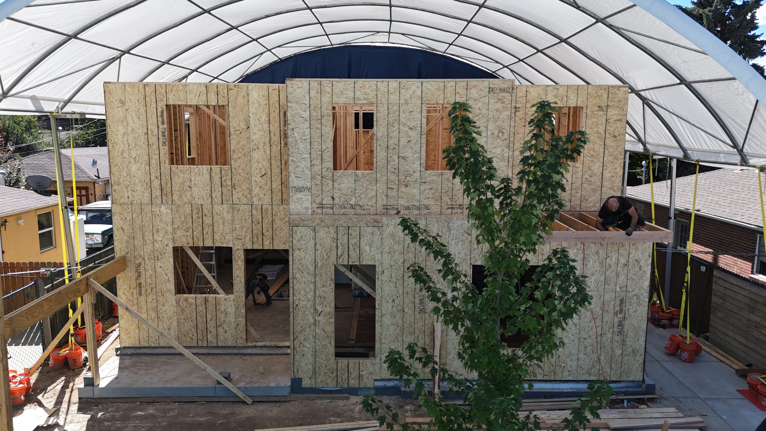 Custom home construction with tarp erected over framing